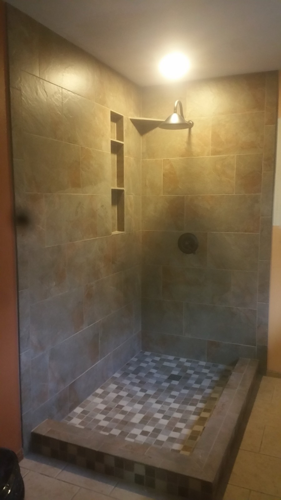Slate walk-in shower with a pebble mosaic floor and a recessed niche