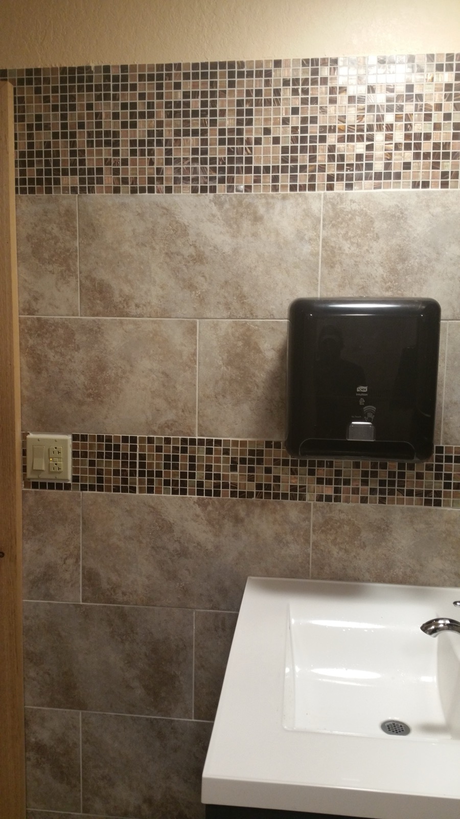 Commercial restroom with full tile and a wall-mounted sink