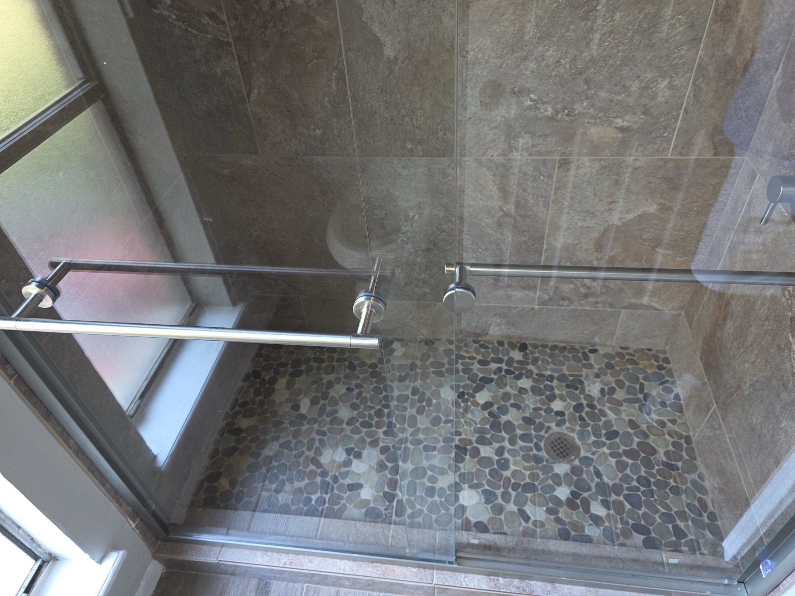 Wide slate shower with pebble floor and glass panel